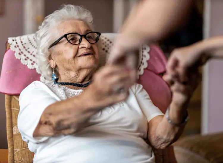 Elderly woman holding hands of support worker